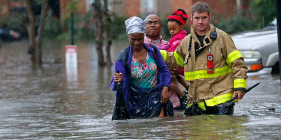 A Louisiana firefighter escorts a family to safety following the community's flood. Image Credit: CBS